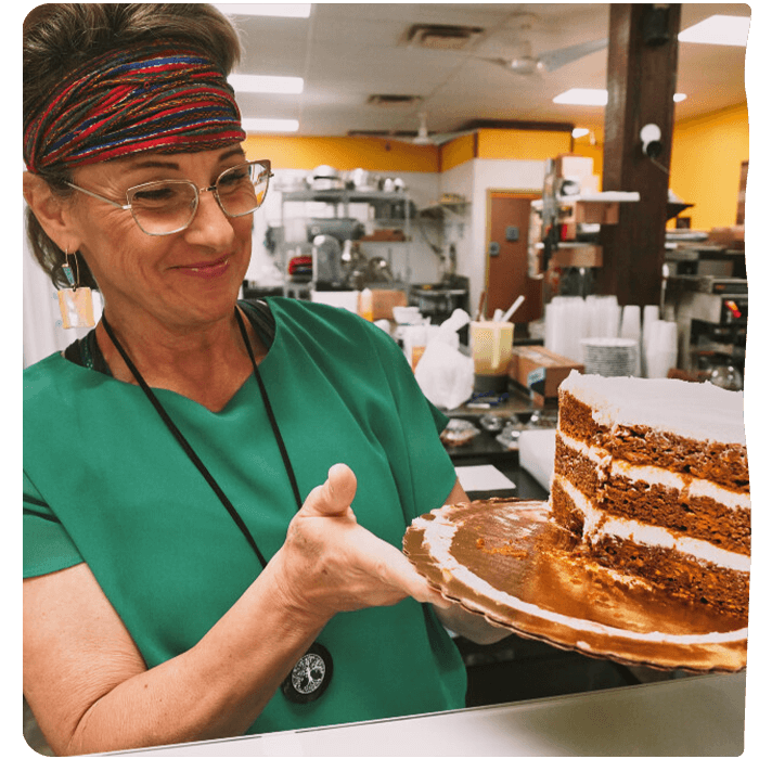 Employee holding a cake. Pyure Commercial Sweeteners are great for bakeries that offer no sugar or keto options.