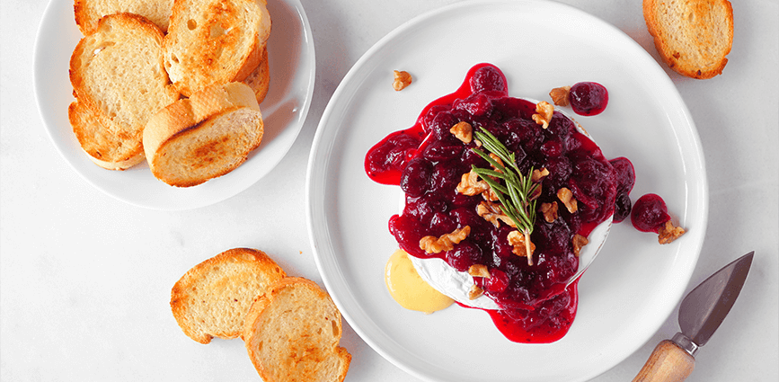Baked Brie with Homemade Low-Sugar Cranberry Sauce on a plate with baguettes