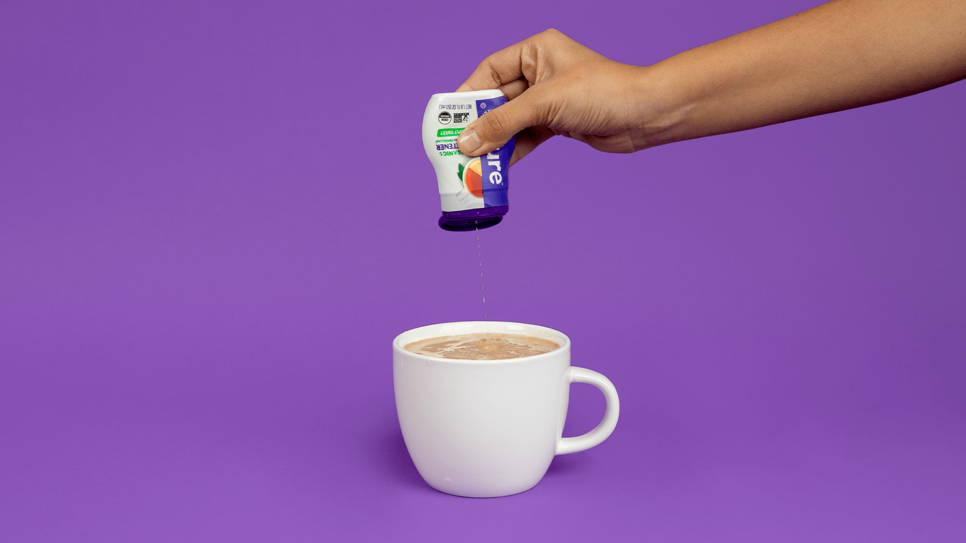 Hand squeezing Pyure Liquid Stevia into cup of coffee