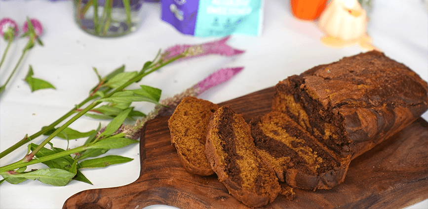 Pumpkin Chocolate Swirl Bread made with Allulose on wooden cutting board with flowers