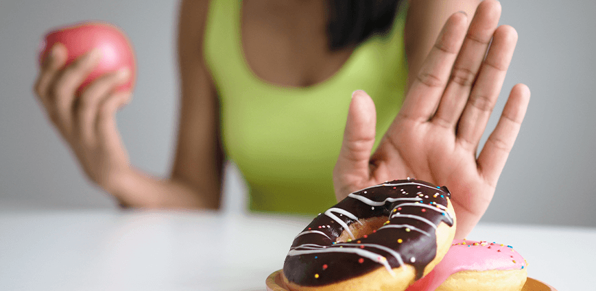 Woman pushing away donut to represent conquering sugar withdrawal