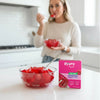 Woman eating raspberry-flavored jel dessert with a box of Pyure jel dessert mix on a kitchen counter.